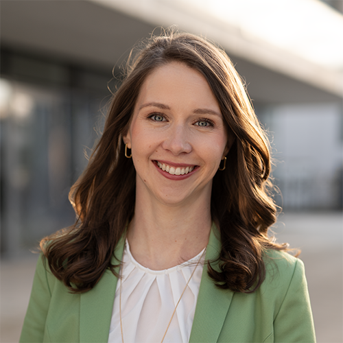 Professionelles Businessportrait einer jungen Frau mit grünem Blazer und freundlichem Lächeln, aufgenommen im weichen Abendlicht in Gießen.