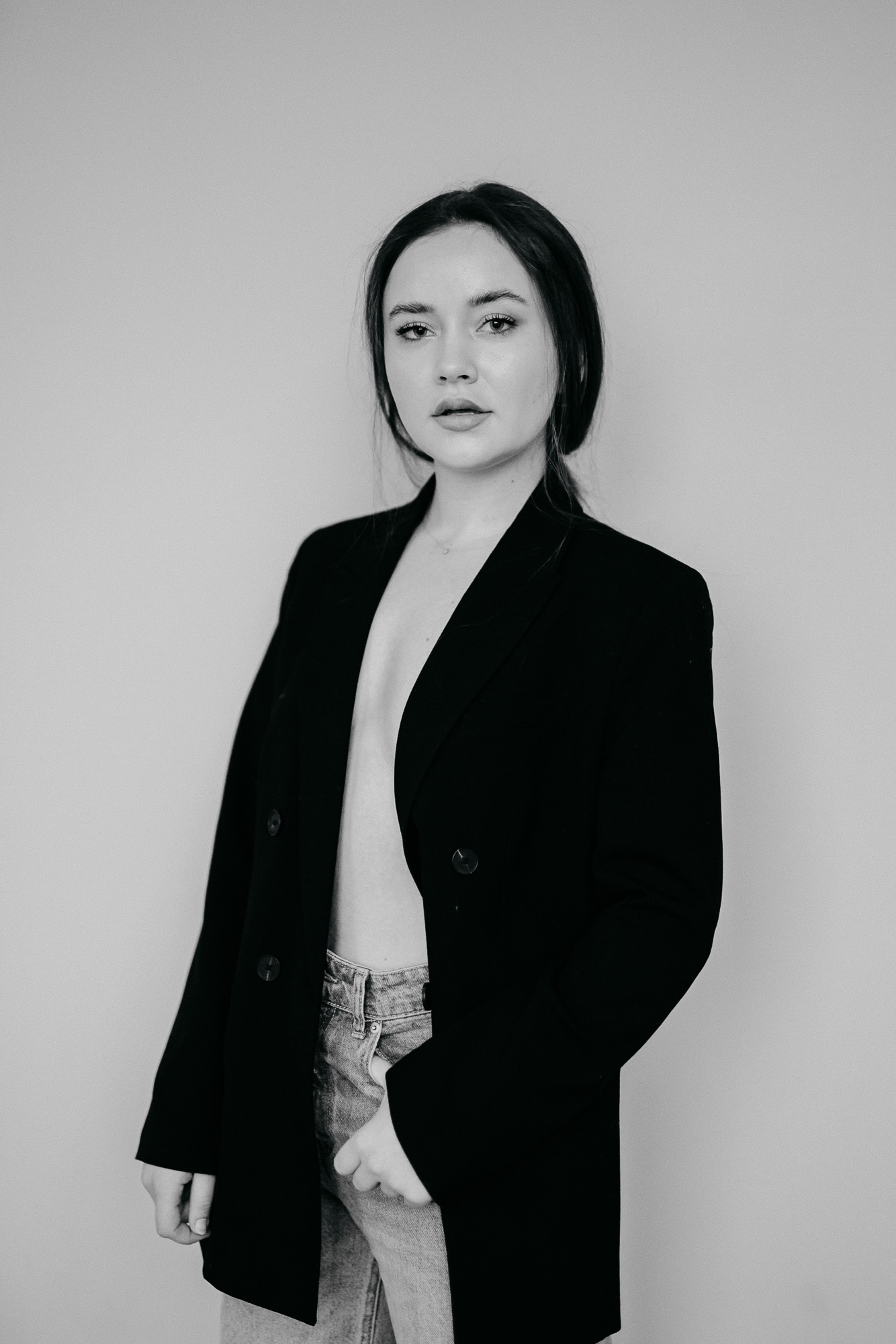 Schwarzweiß-Portrait einer jungen Frau im Oversize-Blazer vor hellem Hintergrund, aufgenommen im modernen Editorial- und Personal-Branding-Stil.